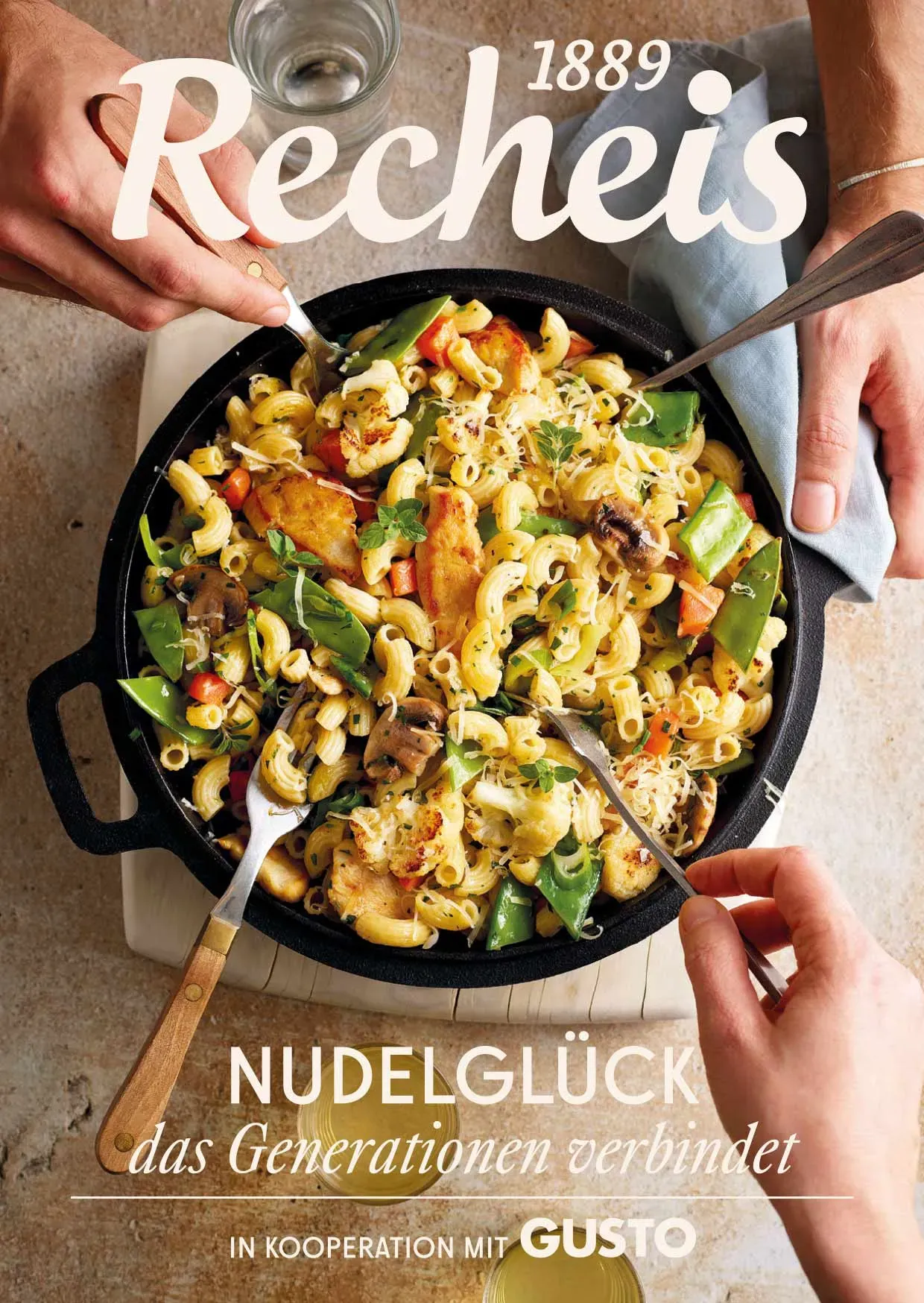 Drei Hände greifen mit Besteck in eine Pfanne mit Nudelgericht und Gemüse, aus dem Rezeptheft Gusto von Recheis