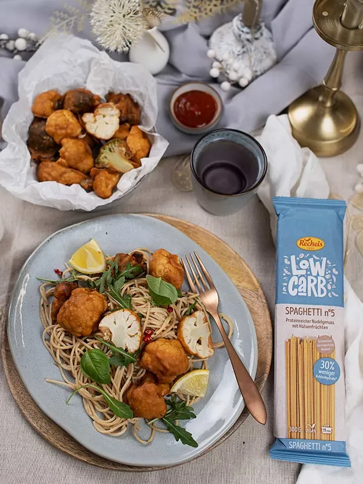 Spaghetti mit Blumenkohl-Wings und Zitronenscheiben auf einem Teller neben einer Low-Carb-Spaghetti-Packung