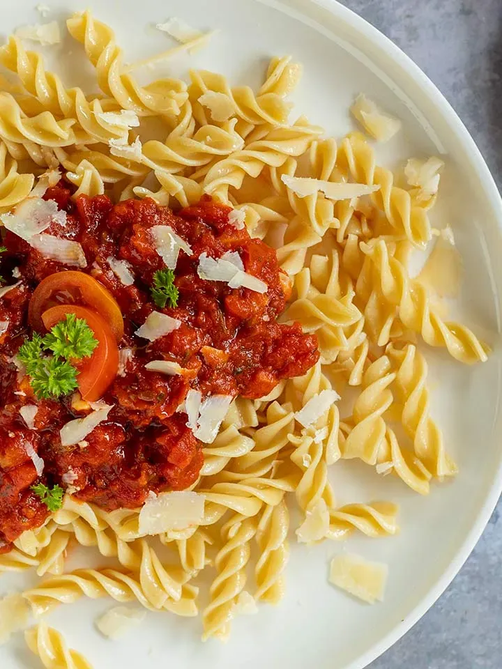 Arrabbiata selber machen: Spiralnudeln mit Tomatensauce, Parmesan und Petersilie auf einem Teller