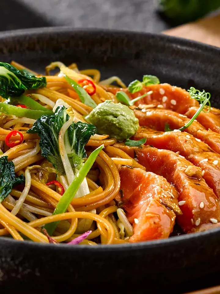 Asia-Spaghetti mit Matcha-Wasabi-Dip: Schüssel mit gebratenen Nudeln, Gemüse und rohem Lachs