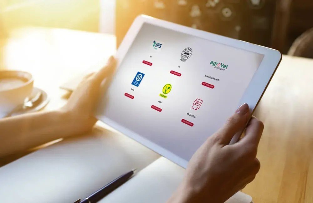 Person hält Tablet mit verschiedenen Zertifizierungslogos auf dem Bildschirm