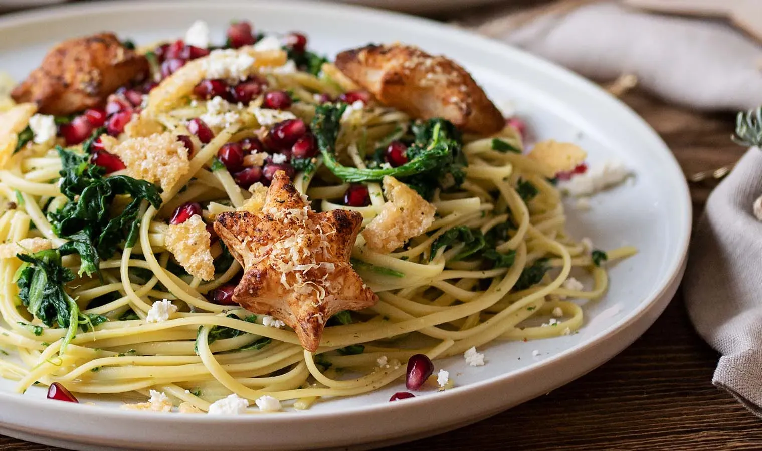 Spaghetti mit Grünkohl und Granatapfelkernen, dazu Blätterteig-Parmesan-Sterne, auf einem Teller