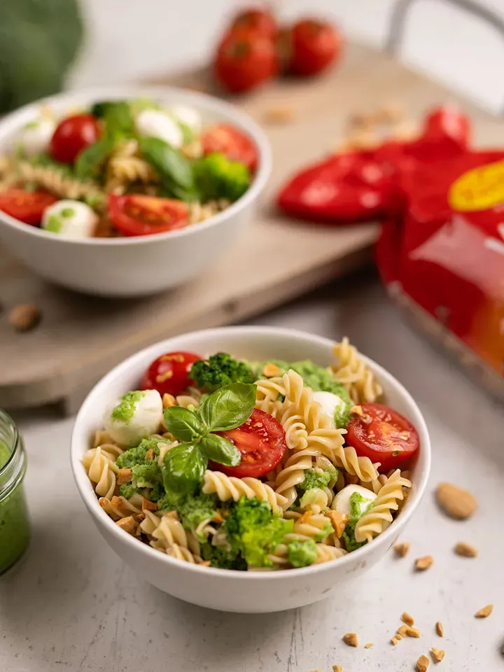 Brokkoli-Basilikum-Pesto: zwei Schalen Fusilli-Nudelsalat mit Tomaten, Mozzarella und grünem Pesto