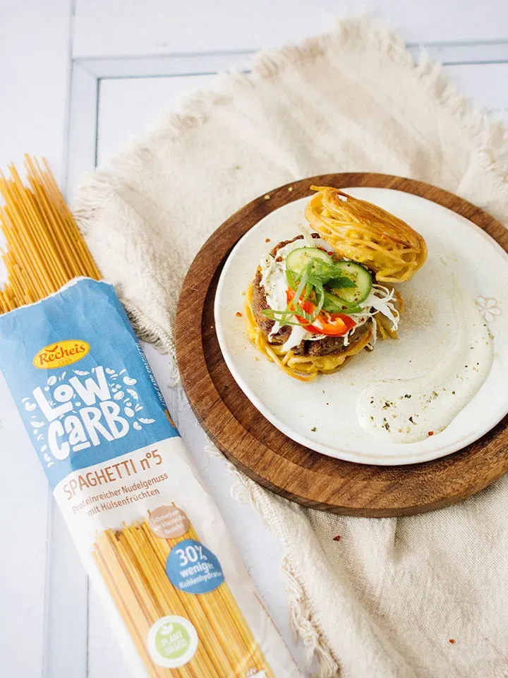 Burger aus Spaghetti mit Gemüse und Sauce, dazu Low-Carb-Spaghetti auf einem Teller
