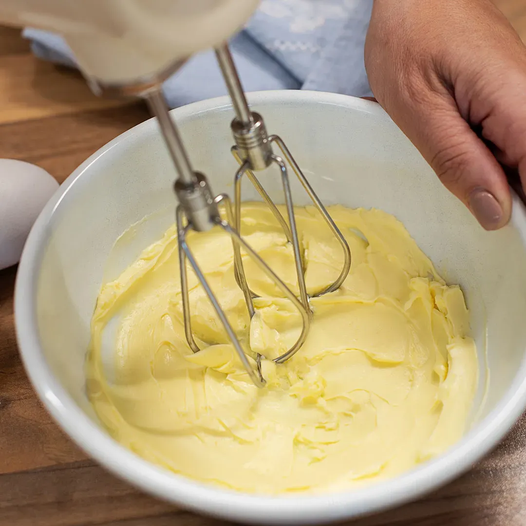 Butter-Grießnockerl: Handrührgerät schlägt cremige Butter in einer weißen Schüssel