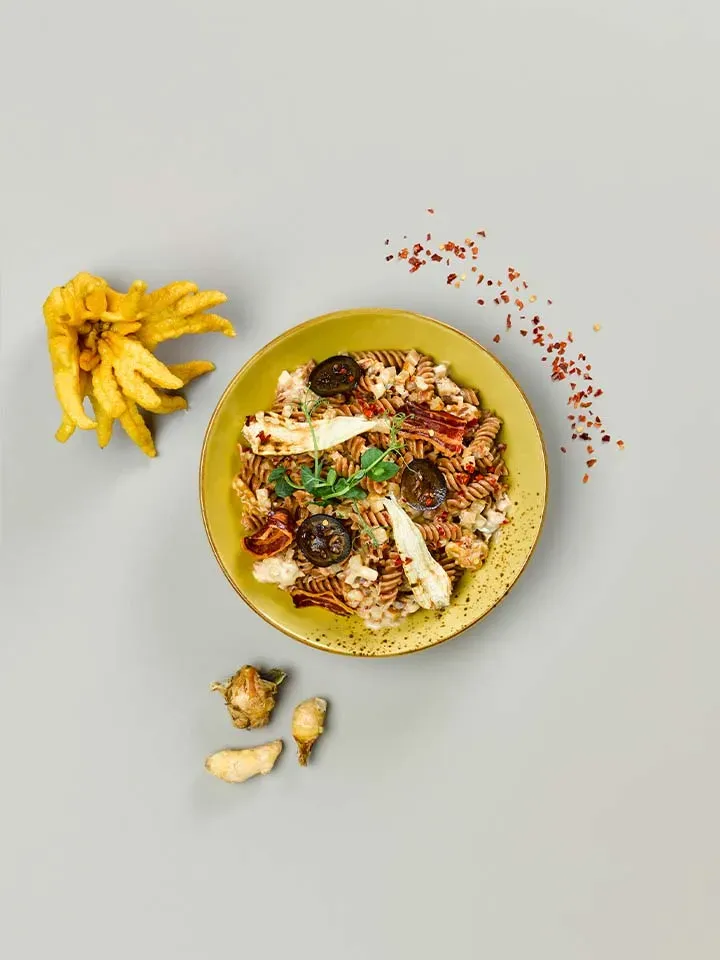 Carbonara mit Birnen, Nudeln mit Gemüse und Gewürzen auf einem Teller auf hellgrauem Hintergrund
