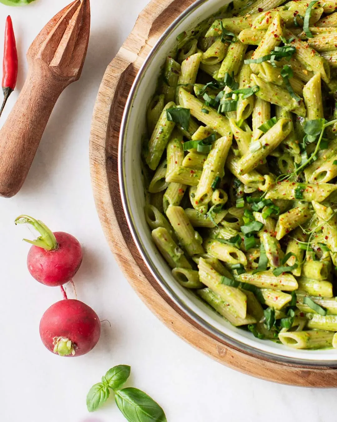 Cremige Bärlauch-Nudelpfanne mit grünen Penne und frischen Kräutern in einer Schale auf Holzunterlage