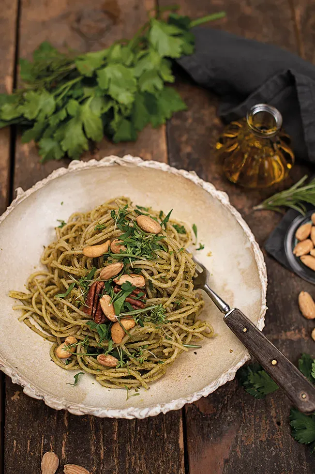 Dinkel Spaghettini mit Kräuter-Nuss-Pesto auf einem Teller auf rustikalem Holztisch