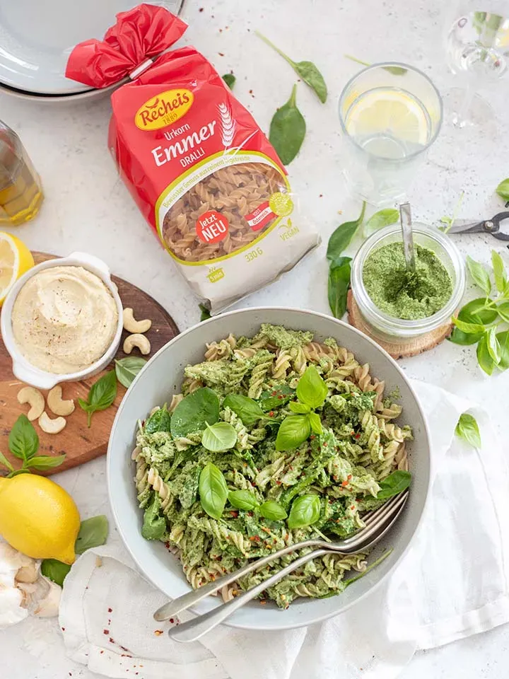 Dralli mit Spinatpesto, Cashew und Ricotta auf Teller neben Nudelpackung und Zutaten auf Tisch