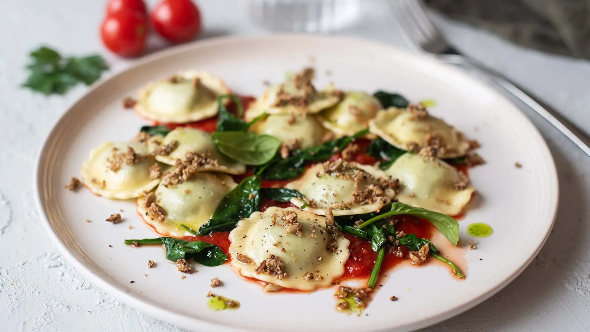 Fiori mit Spinat und Sonnenblumenkernen als Knuspertopping auf Tomatensauce, mit Kräutern garniert