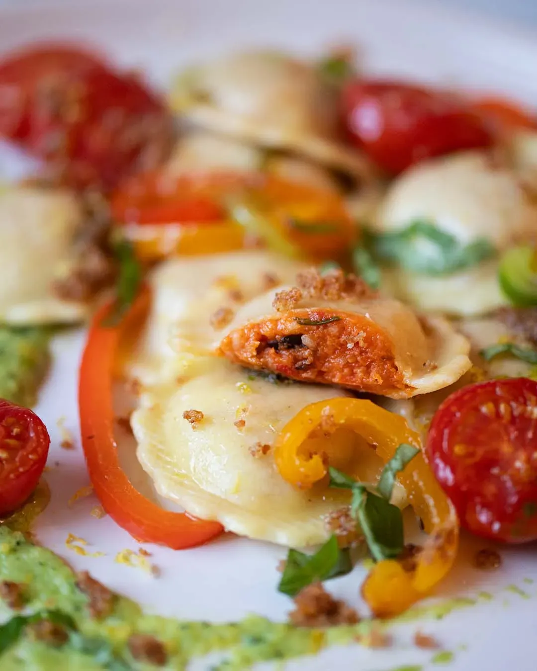 Nahaufnahme: vegane Fiori Peperonata mit Zucchinicreme, Tomaten und Paprikastreifen auf einem Teller