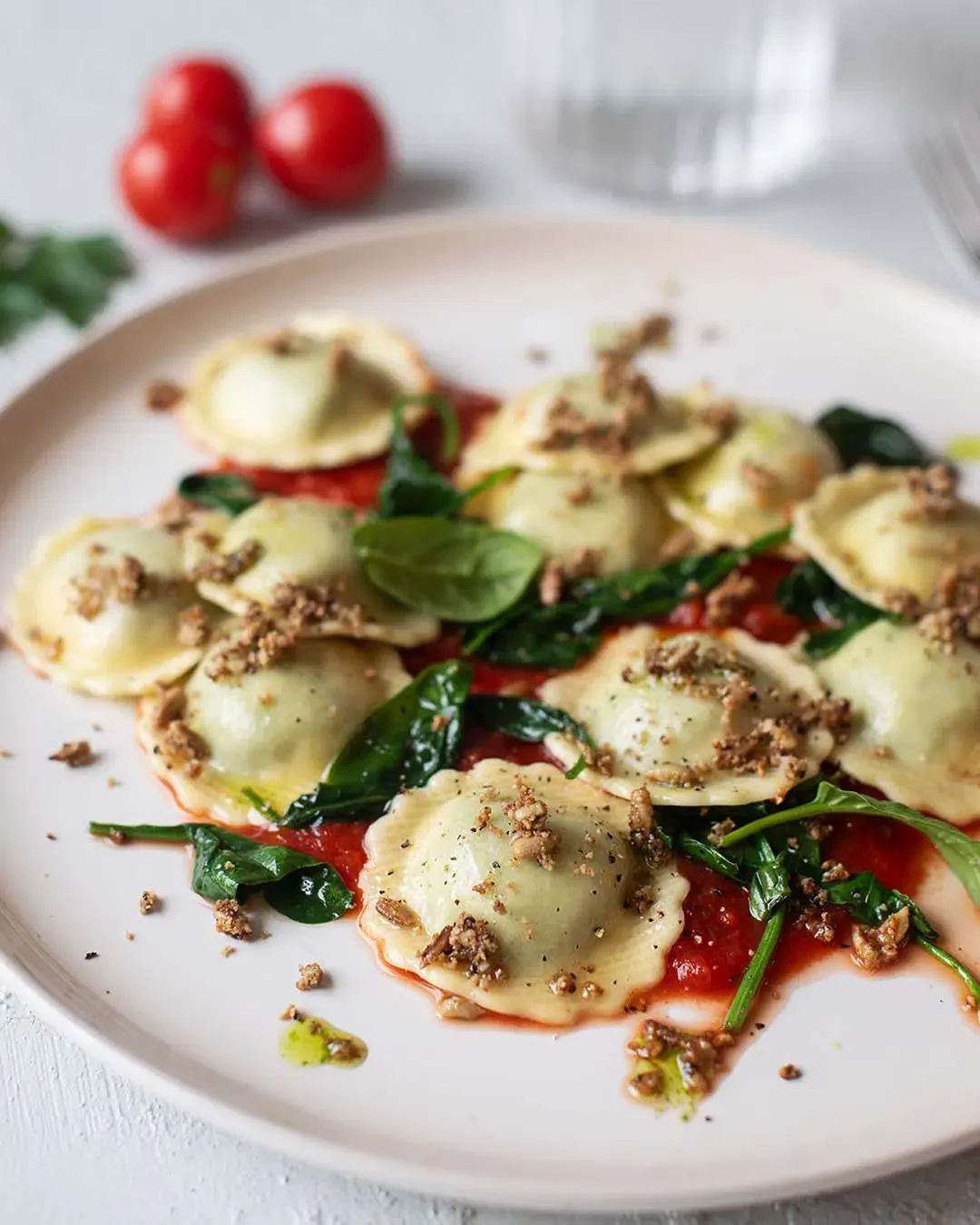 Fiori mit Spinat und Sonnenblumenkernen auf Tomatensauce, mit Nüssen garniert