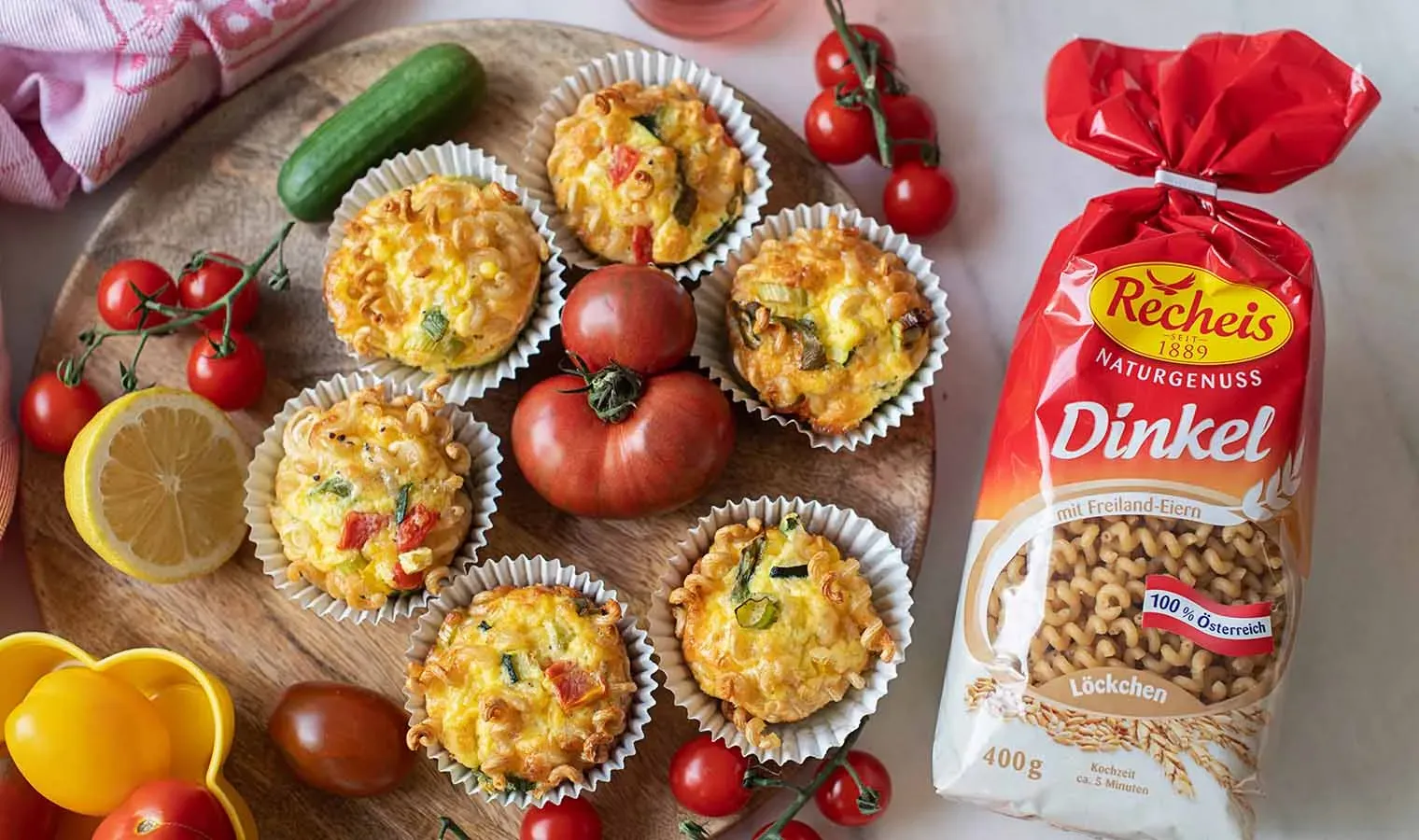 Frittata-Muffins mit Gemüse und Nudeln neben einer Packung Dinkelpasta und frischem Gemüse