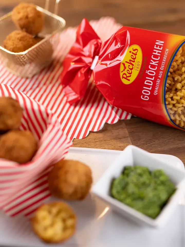 Frittierte Nudelbällchen mit grünem Dip neben einer Packung Goldlöckchen Nudeln