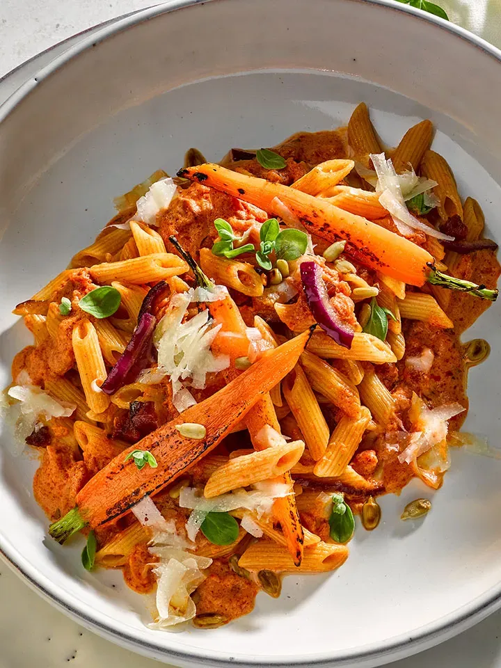 Alpenglühen Hütten-Penne in roter Sauce mit gegrillten Karotten und Kräutern auf Teller
