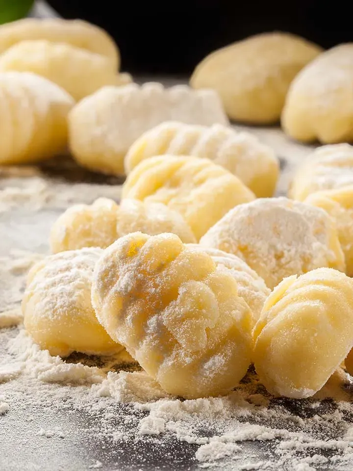 Hausgemachte rohe Gnocchi, mit Mehl bestäubt, auf einer Arbeitsfläche