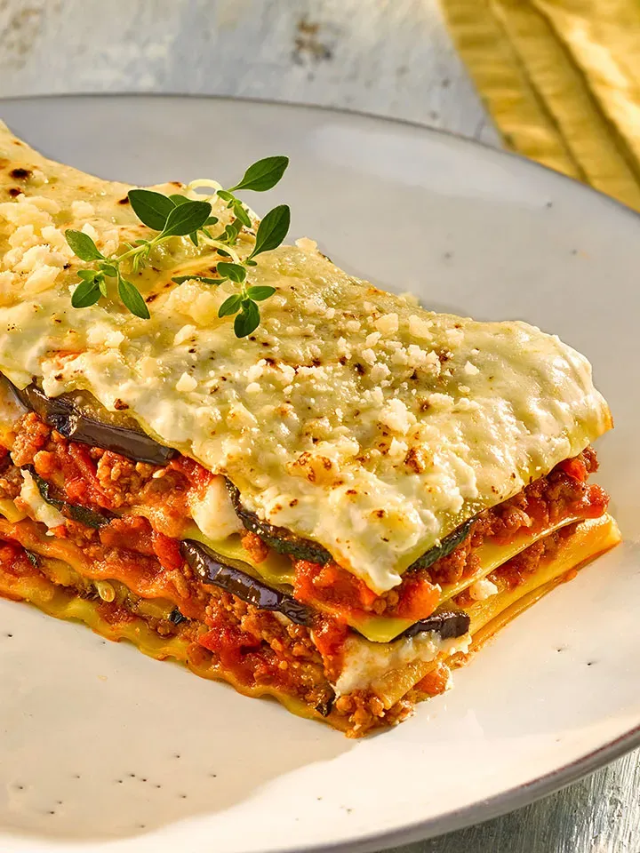 Lasagne al forno mit Faschiertem, Fleischsauce und Käse auf einem weißen Teller, Gastrorezept
