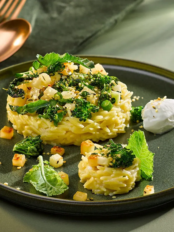 Risotto mit Brokkoli und Schafskäse: kreisförmige Portionen mit grünem Gemüse und einem Klecks Creme