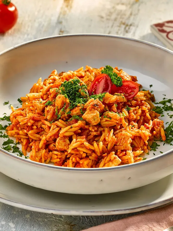 Nudelreisfleisch mit Putenbrust, Tomaten und Petersilie auf einem Teller, Gastrorezept