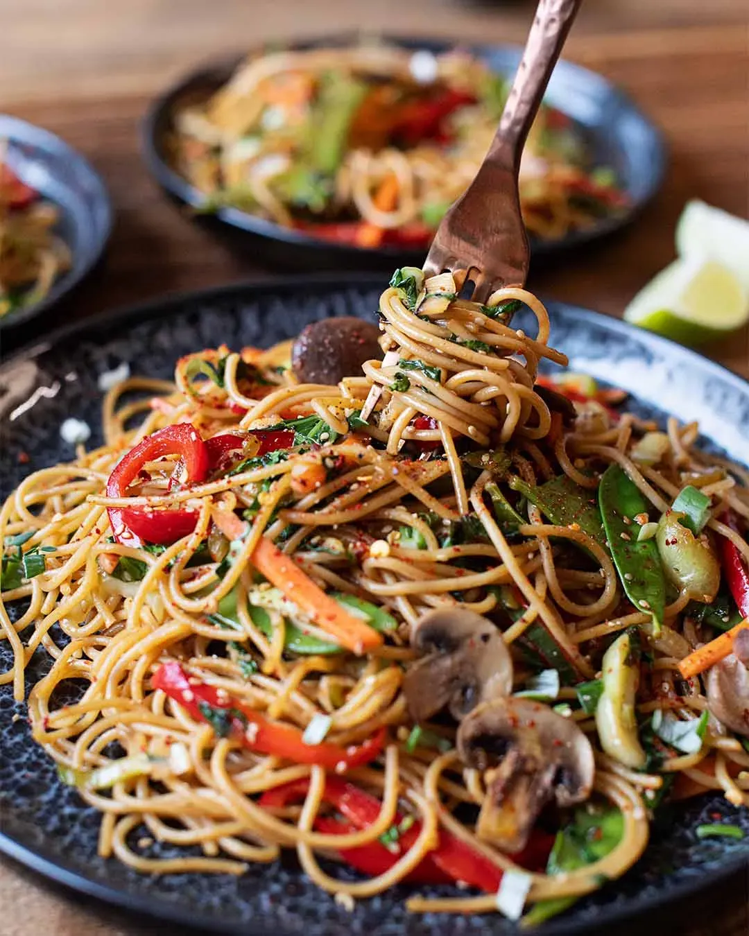 Gabel mit gebratenen Asia-Spaghetti und Gemüse über einem Teller