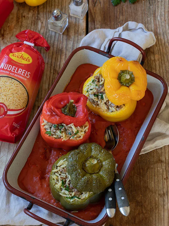 Gefüllte Paprika mit Reis und Hackfleisch in einer Auflaufform auf Holztisch