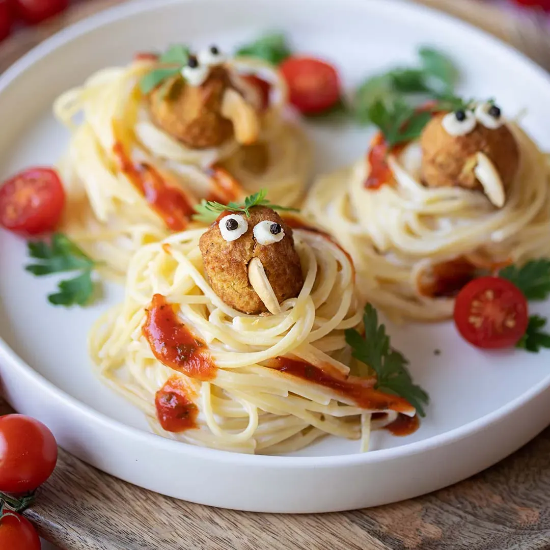 Gemüsebällchen-Vögel in Spaghettinestern, als Mammuts mit Augen und Stoßzähnen dekoriert, auf einem Teller