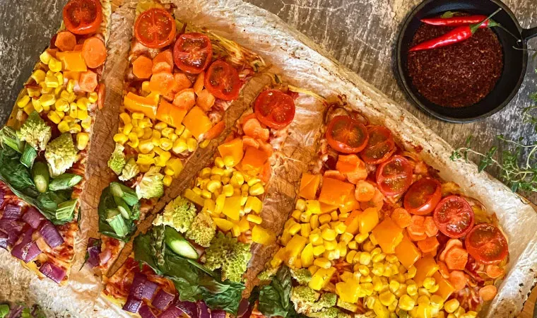 Gemüsepizza aus Spaghetti in Regenbogenfarben, mit scharfer Sauce und Chili