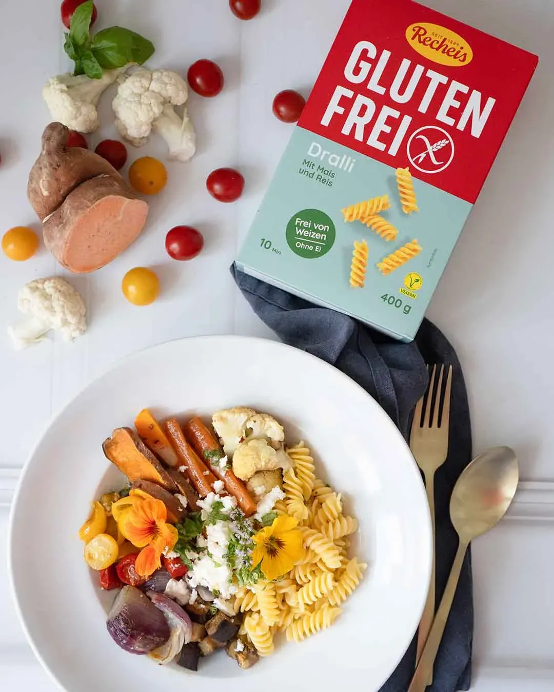 Glutenfreie Nudelbowl mit Gemüse auf einem Teller neben einer Packung glutenfreier Nudeln