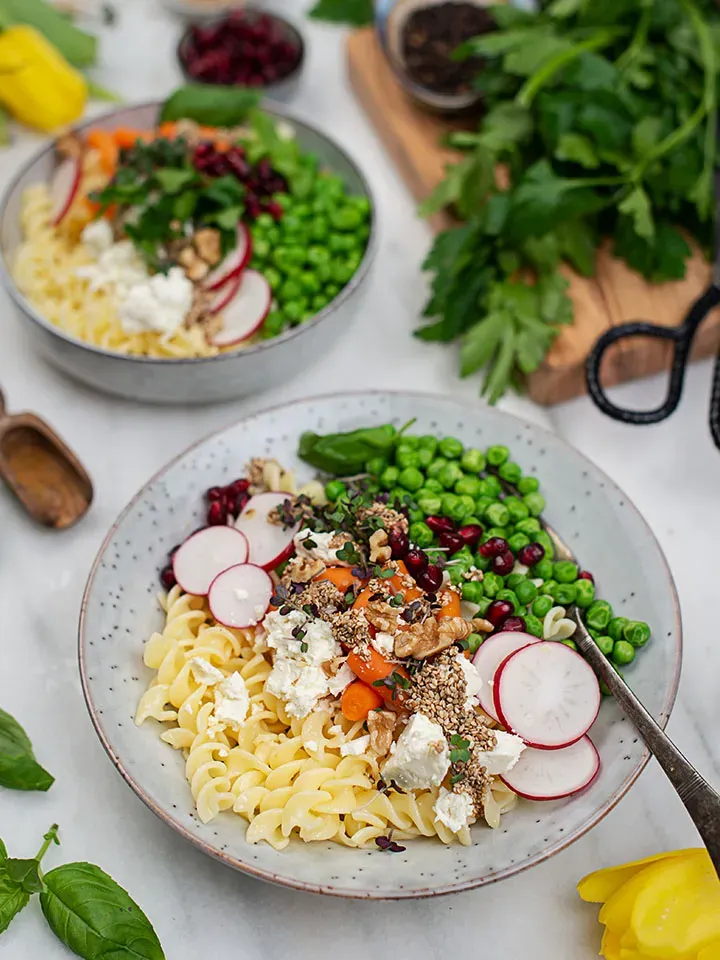 Glutenfreie Pastabowl mit Nudelsalat, Erbsen, Radieschen, Feta, Walnüssen und Granatapfelkernen