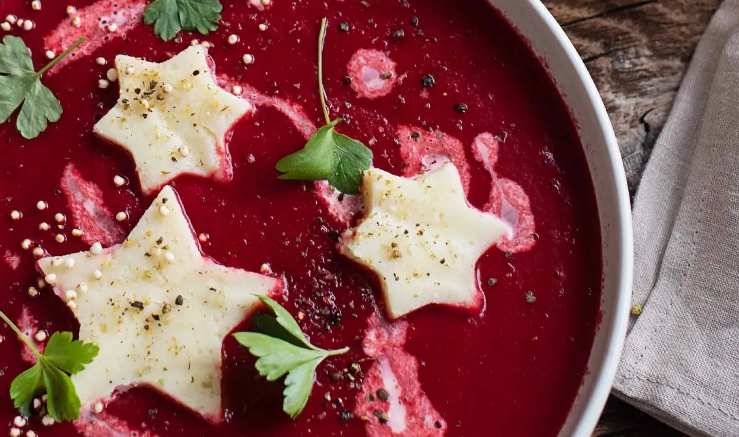 Grießsterne aus Nockerlgrieß in roter Suppe, mit grünen Kräutern garniert
