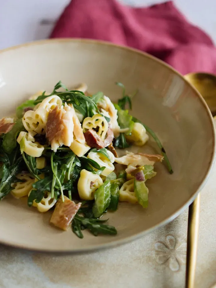 Herzerlnudeln mit Alpenfisch und grünem Salat auf einem Teller angerichtet