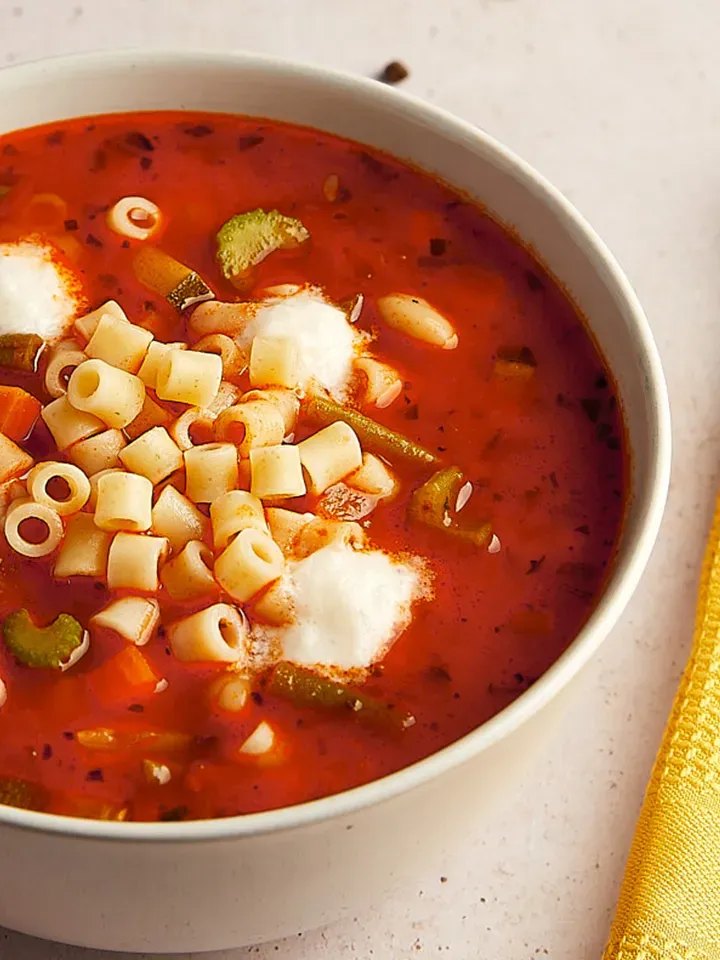 Nahaufnahme: herzhafte Minestrone mit Ditalini und Gemüse in einer Schüssel auf hellem Untergrund
