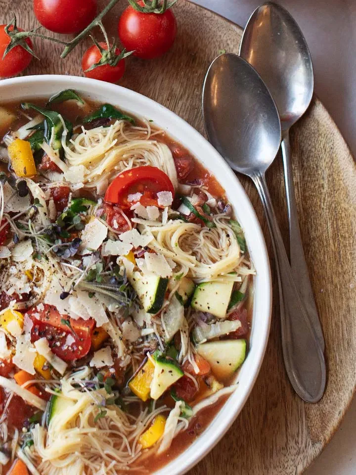 Instant-Suppe mit Nudeln und Parmesan in einer Schüssel auf Holztablett mit zwei Löffeln