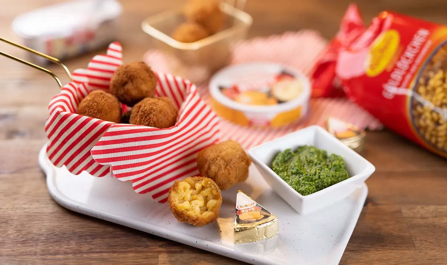 Frittierte Käse-Nudelbällchen mit Dip und Käse auf Holzuntergrund