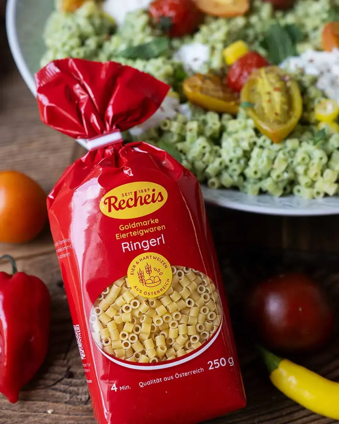 Packung Recheis Goldmarke Ringerl vor einer Schale Joghurt-Nudeln mit Ofentomaten