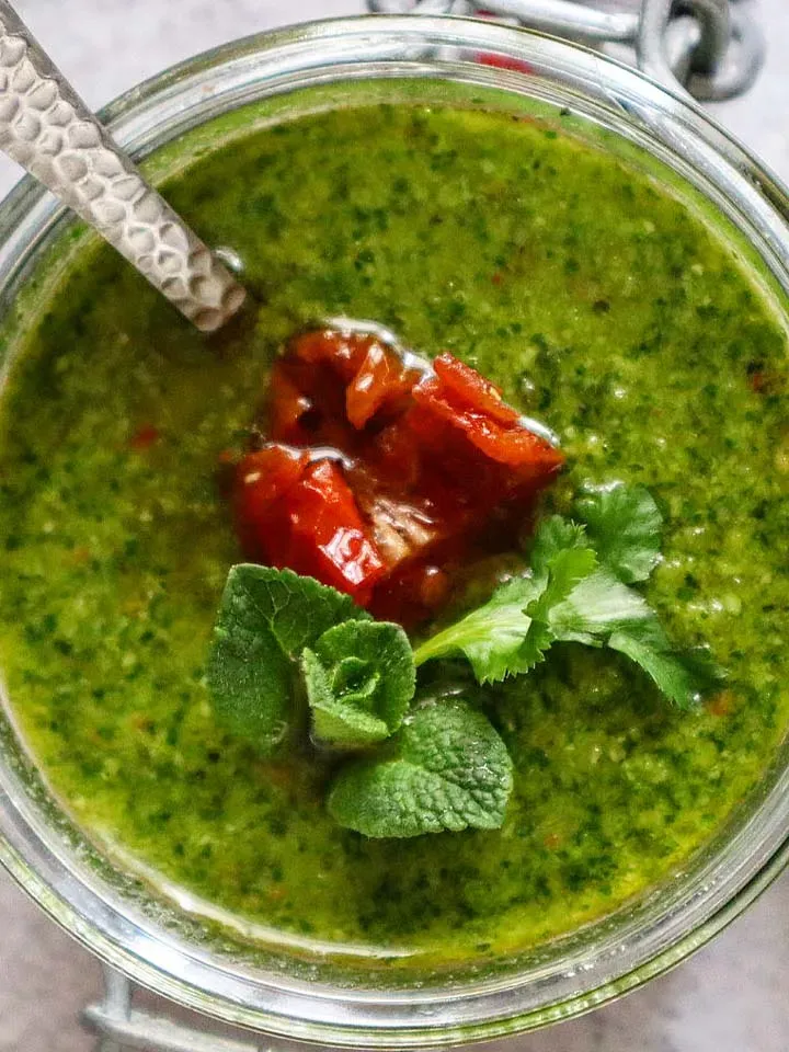 Koriander-Minz-Pesto als grünes Chutney mit getrockneten Tomaten und frischen Kräutern im Glas
