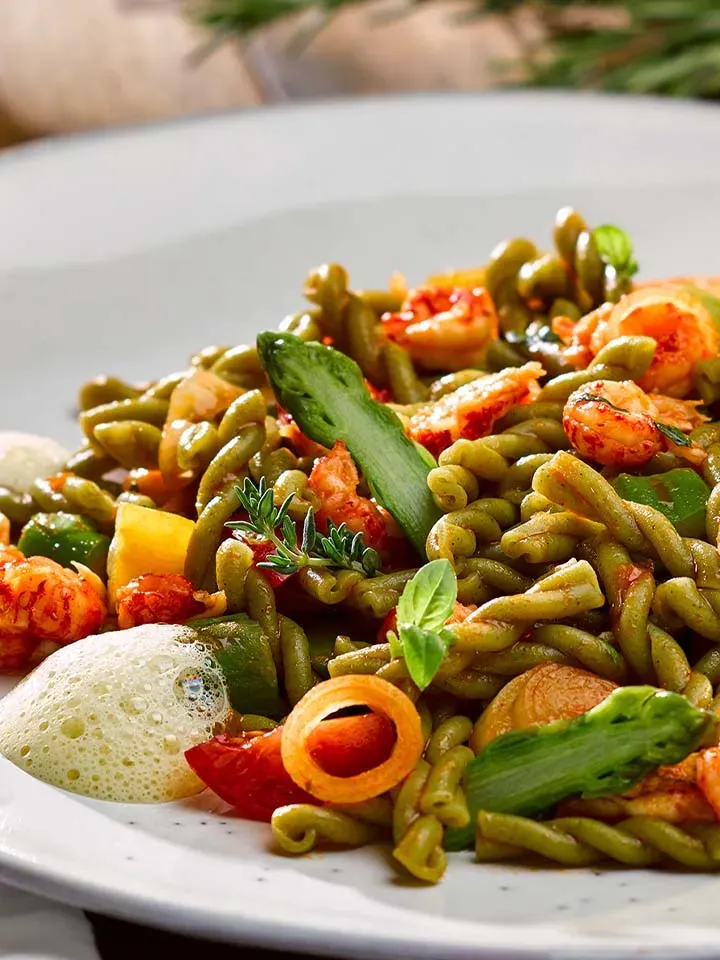 Kräuter-Treccine mit Flusskrebsen, Spargel und Kräutern auf einem Teller