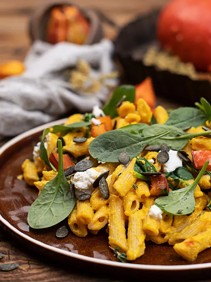 Kürbis-Ricotta-Pasta mit Spinat, Kürbiskernen und Frischkäse auf einem Teller