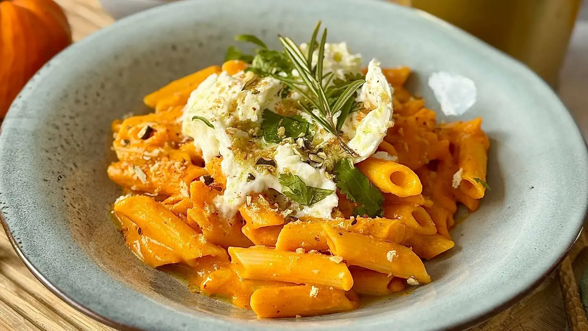 Nahaufnahme der cremigen Kürbis-Penne mit Burrata, Rosmarin und Kürbiskern-Crunch