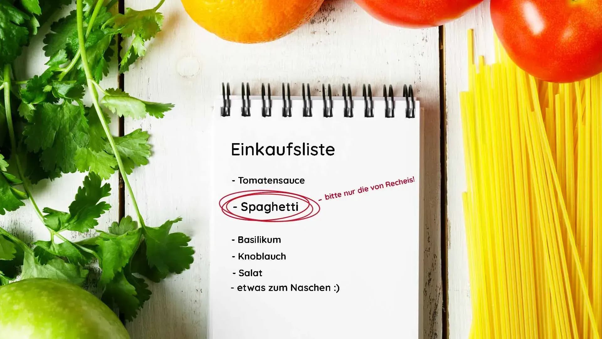 Notizblock mit Einkaufsliste zwischen Spaghetti, Tomaten, Orangen und Petersilie
