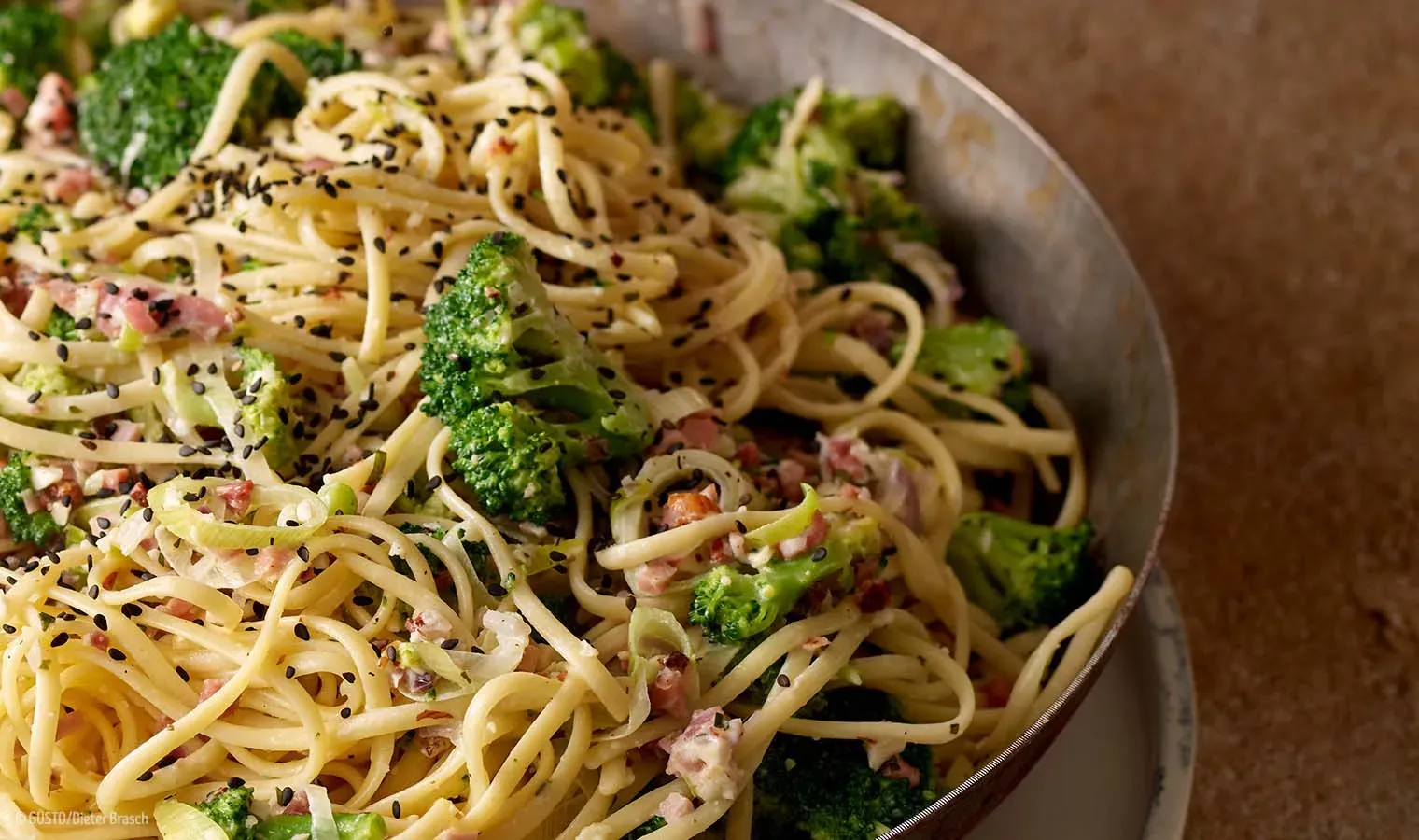 Nahaufnahme von Linguine mit weißem Pesto, Brokkoli und Speck in der Pfanne