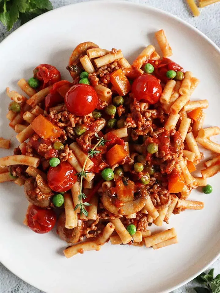 Low-Carb-Hirtenmakkaroni mit Tomaten, Erbsen, Hackfleisch und Pilzen, mit Thymian garniert