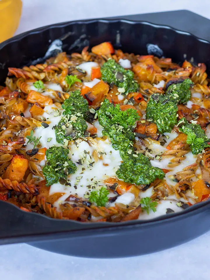 Low-Carb-Nudelauflauf mit Kürbis, Grünkohl, Käse und grünem Pesto in schwarzer Form