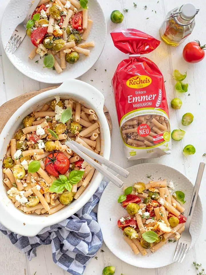 Emmer-Makkaroni mit Kohlsprossen und Feta aus dem Ofen auf Teller und in Auflaufform neben Nudelpackung