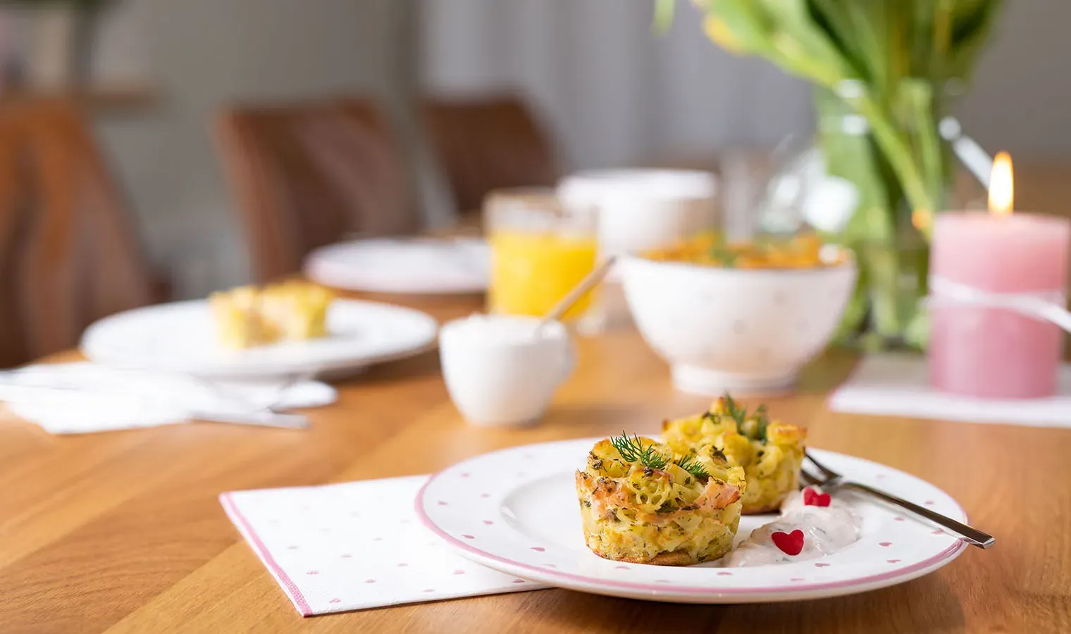 Nudelmuffins mit Lachs in Herzform auf Teller mit Deko auf gedecktem Holztisch