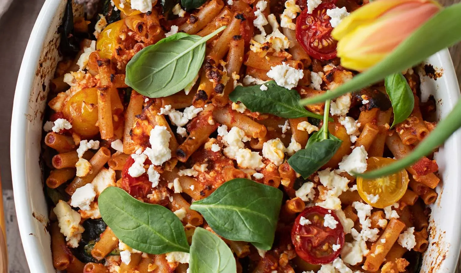 Nudelauflauf mit Gemüse: überbackene Pasta mit Tomaten, Spinat und zerbröseltem Käse in Auflaufform