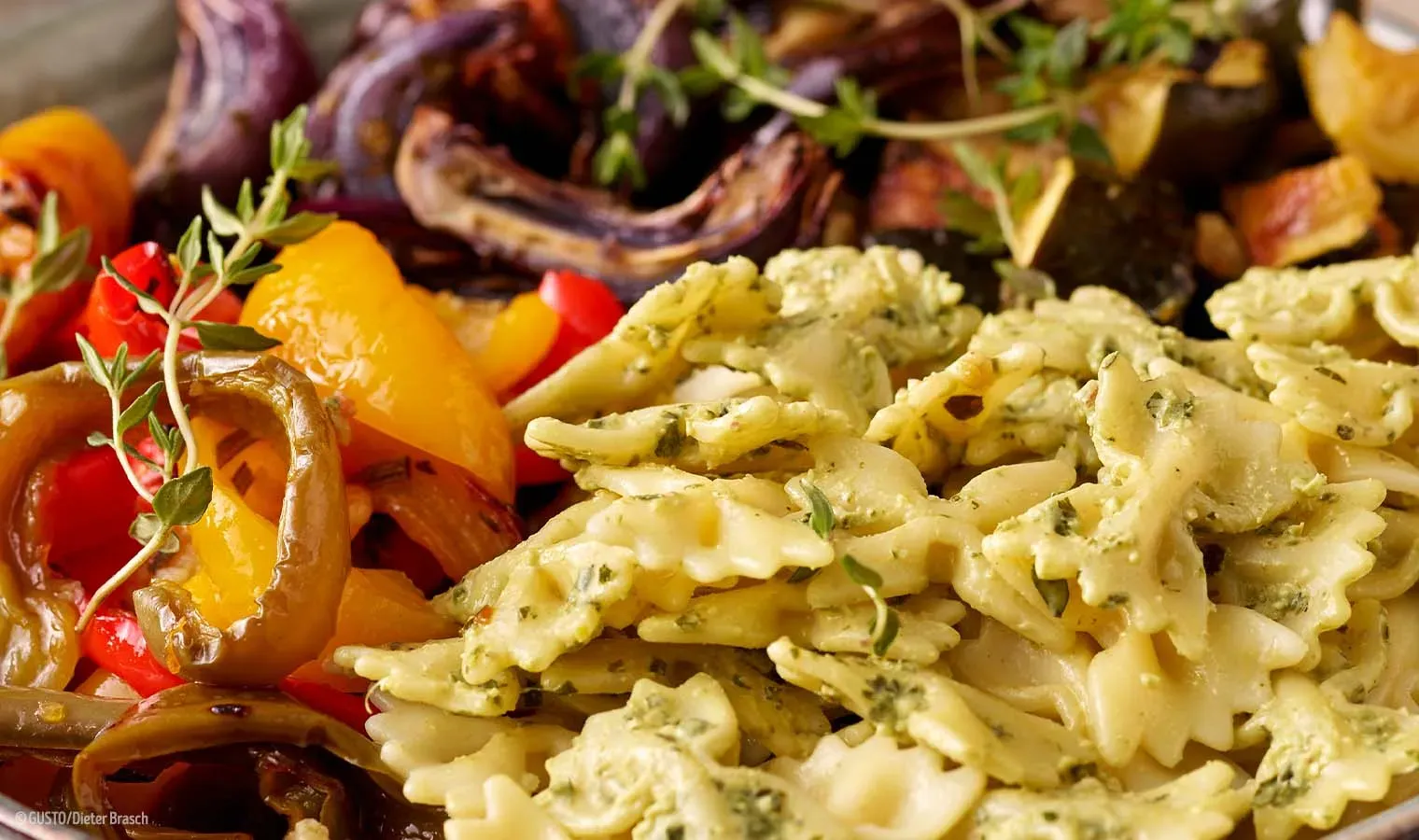 Nahaufnahme einer Nudelbowl mit Farfalle, Kräutern und geröstetem Ofengemüse