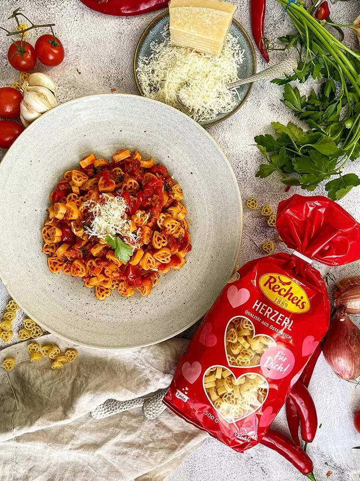 Nudeln all'Amatriciana: herzförmige Pasta mit Tomatensauce, Parmesan und frischen Zutaten auf einem Tisch