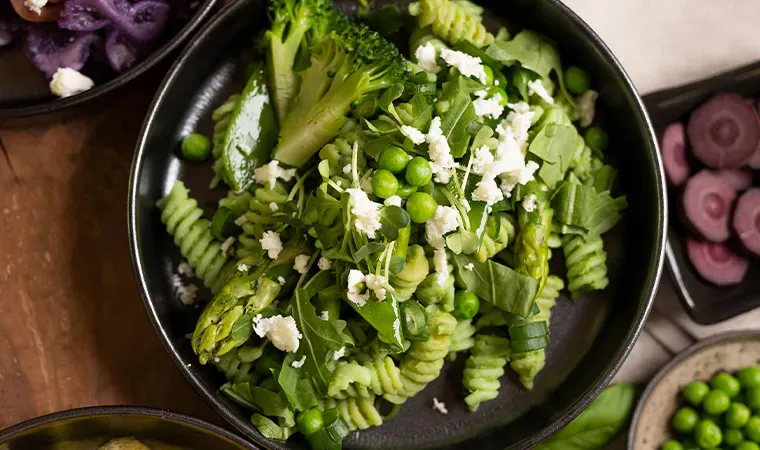 Nudeln mit Erbsen-Cashew-Creme, Spargel und Feta in schwarzer Schüssel