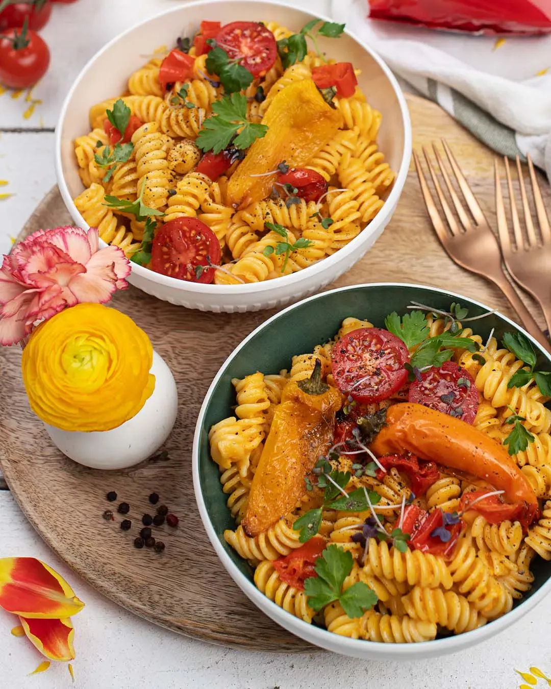 Nudeln mit Paprikasauce: zwei Schalen Fusilli mit Tomaten und Paprika auf einem Holztablett